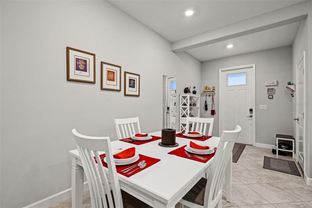 A dining area features a white table with place settings, chairs, and wall art — 6612 CITRUS CREEK LANE, TAMPA, FL