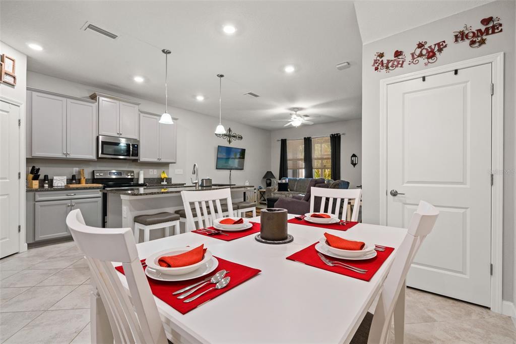 A dining area with a white table and chairs opens into a kitchen with gray cabinets — 6612 CITRUS CREEK LANE, TAMPA, FL