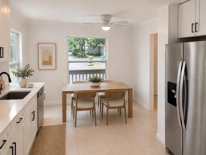 A bright kitchen and dining area features white cabinets, stainless steel appliances, and a wooden table — 1469 19TH STREET, SARASOTA, FL
