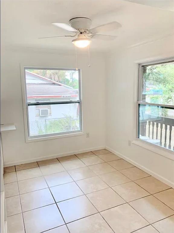 An empty room with white walls, beige tile flooring, a ceiling fan, and two windows — 1469 19TH STREET, SARASOTA, FL
