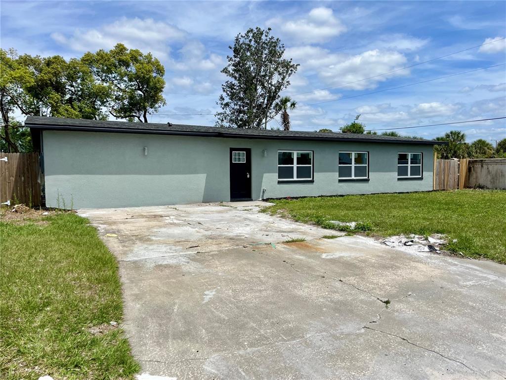 A single-story house with a light green exterior, a black front door, and a concrete driveway — 701 ALFRED DRIVE, ORLANDO, FL