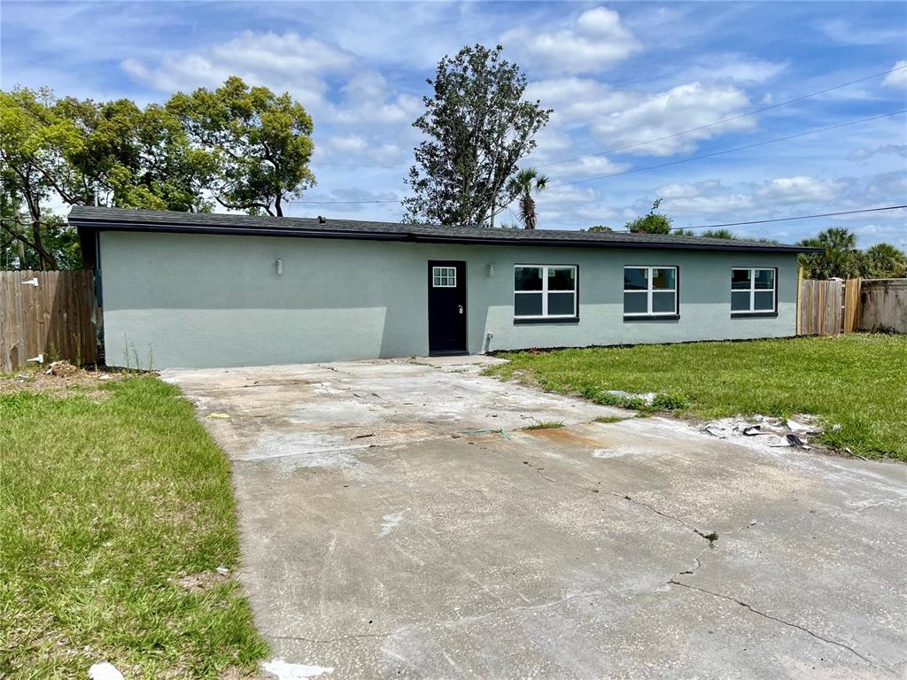 A single-story house with a light green exterior, a black door, and a concrete driveway — 701 ALFRED DRIVE, ORLANDO, FL