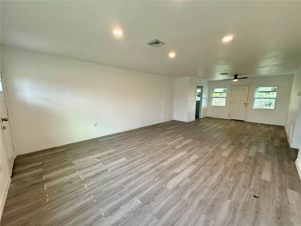 A spacious, empty room features light gray wood-look flooring, white walls, and recessed lighting — 701 ALFRED DRIVE, ORLANDO, FL