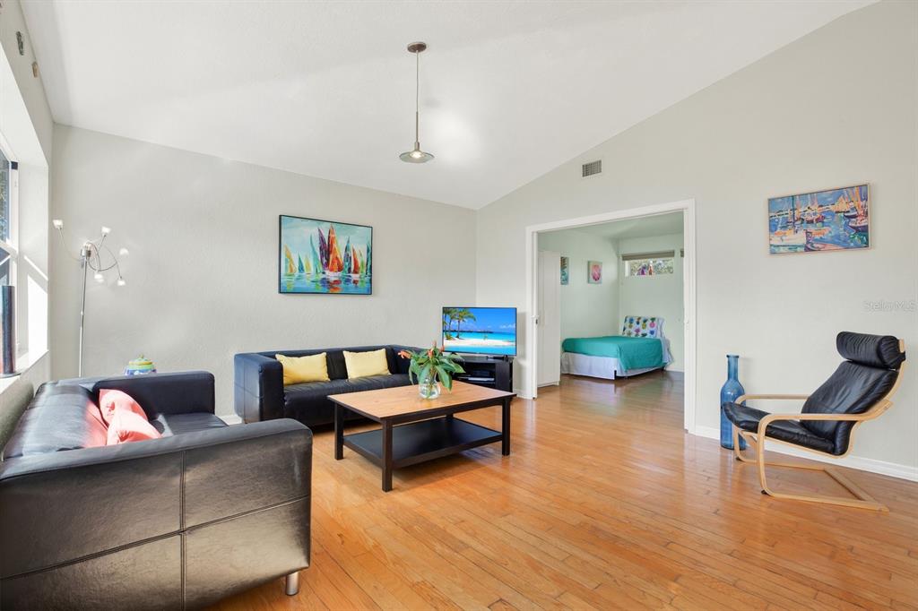 A living room with hardwood floors, black leather furniture, and a view into a bedroom — 201 GEORGIA AVENUE, CRYSTAL BEACH, FL