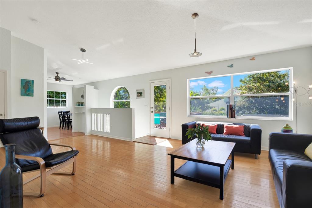 A living room with hardwood floors, black leather furniture, and a large window — 201 GEORGIA AVENUE, CRYSTAL BEACH, FL
