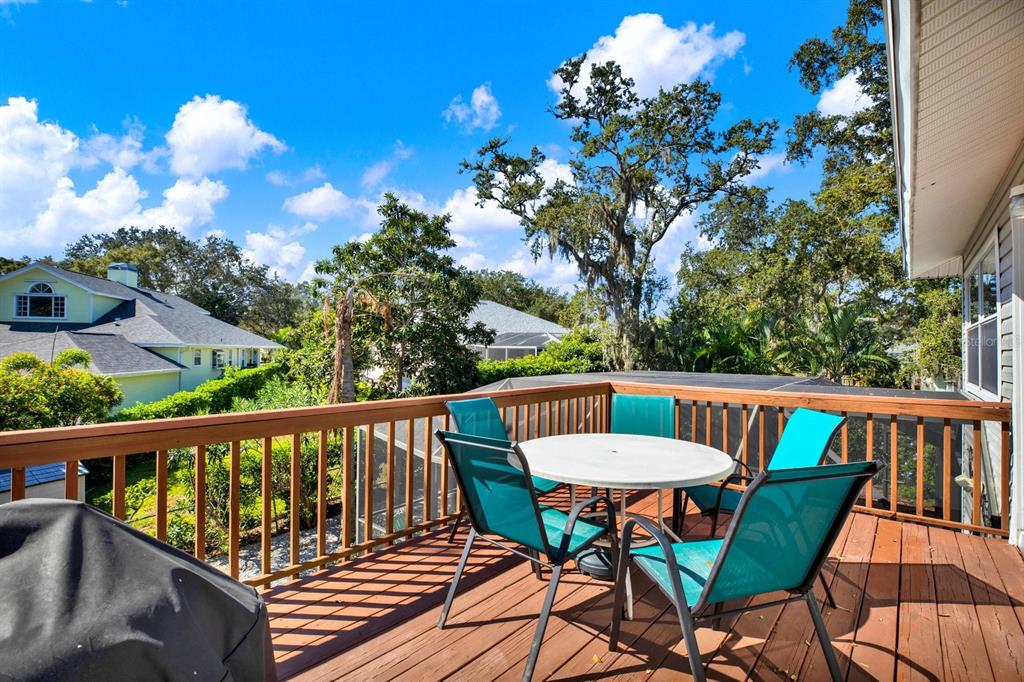 A wooden deck features a round table and four chairs overlooking a residential backyard — 201 GEORGIA AVENUE, CRYSTAL BEACH, FL