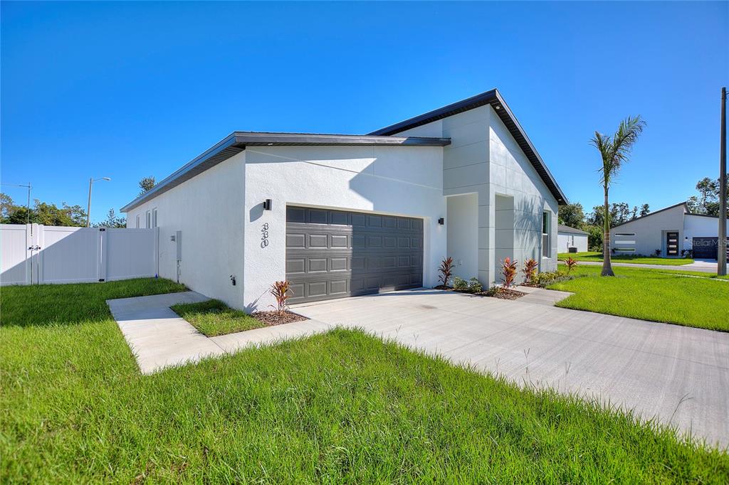 A modern single-story house with a white exterior, gray garage door, and a concrete driveway — 330 ROYAL PALM WAY, WINTER HAVEN, FL