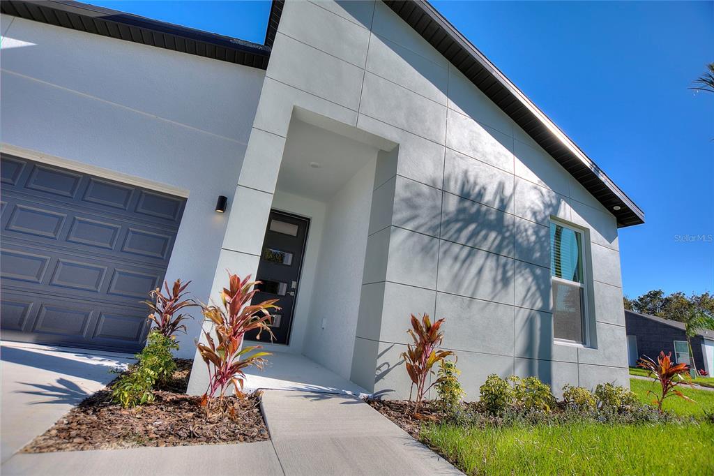 A modern house exterior features a gray garage door, a recessed entryway, and paneled siding — 330 ROYAL PALM WAY, WINTER HAVEN, FL