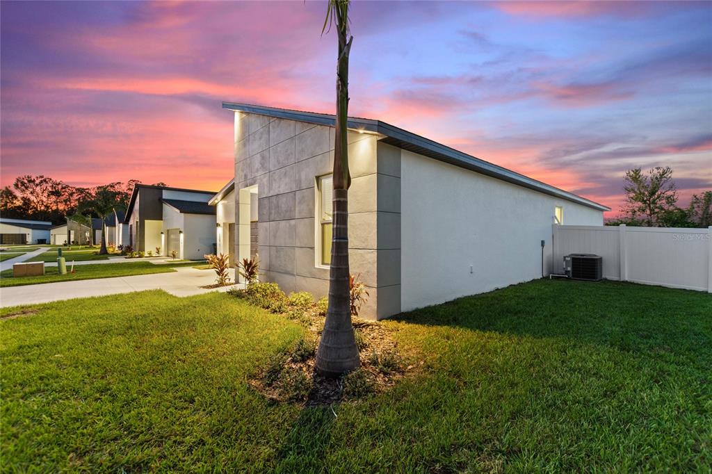 A modern single-story house exterior features a palm tree in the front yard at sunset — 330 ROYAL PALM WAY, WINTER HAVEN, FL
