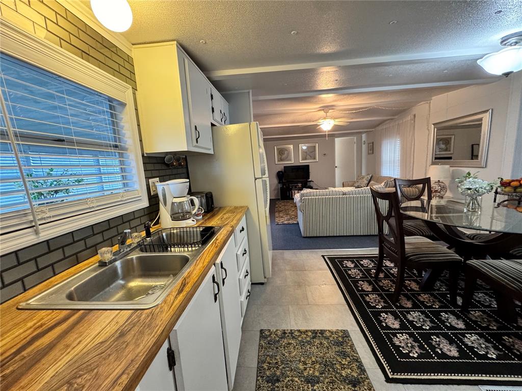 A kitchen with wood countertops and white cabinets opens into a living and dining area — 1710 7TH STREET SW UNIT 2, RUSKIN, FL