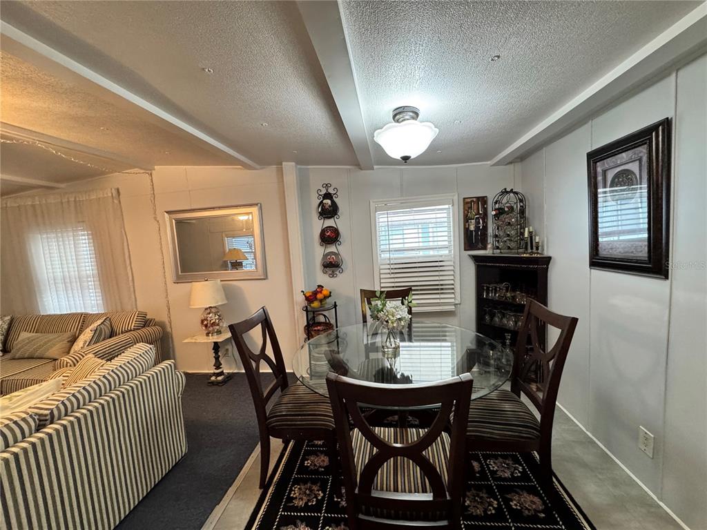 A dining area with a glass table, four chairs, and a nearby living room sofa — 1710 7TH STREET SW UNIT 2, RUSKIN, FL