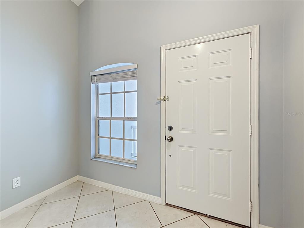An entryway features light blue walls, tile flooring, a white front door, and a window — 3811 WESTERHAM DRIVE, CLERMONT, FL