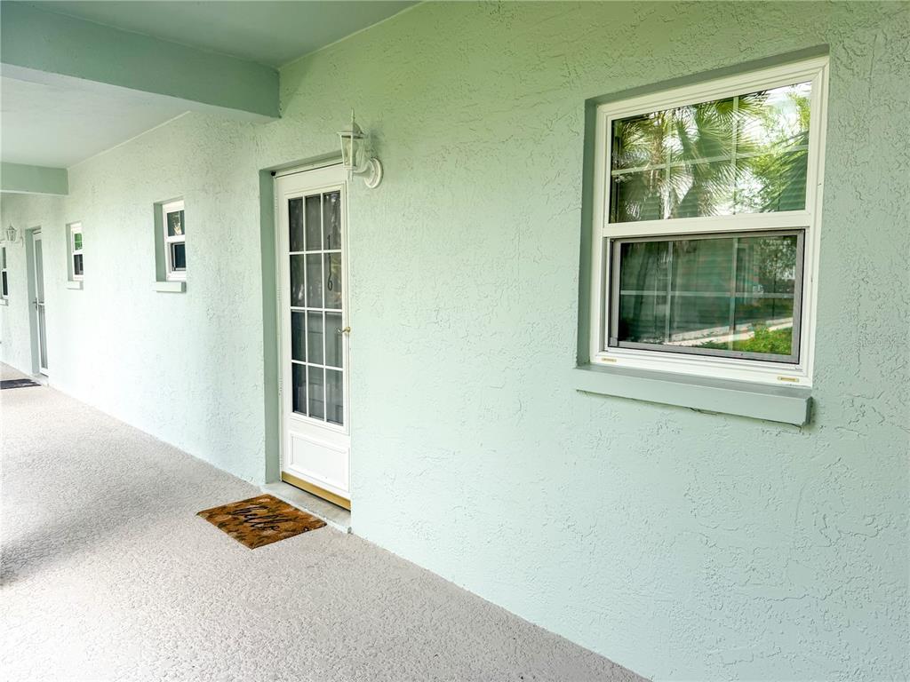 A light green exterior wall features a white door, a window, and a welcome mat — 701 POINSETTIA ROAD UNIT 116, BELLEAIR, FL