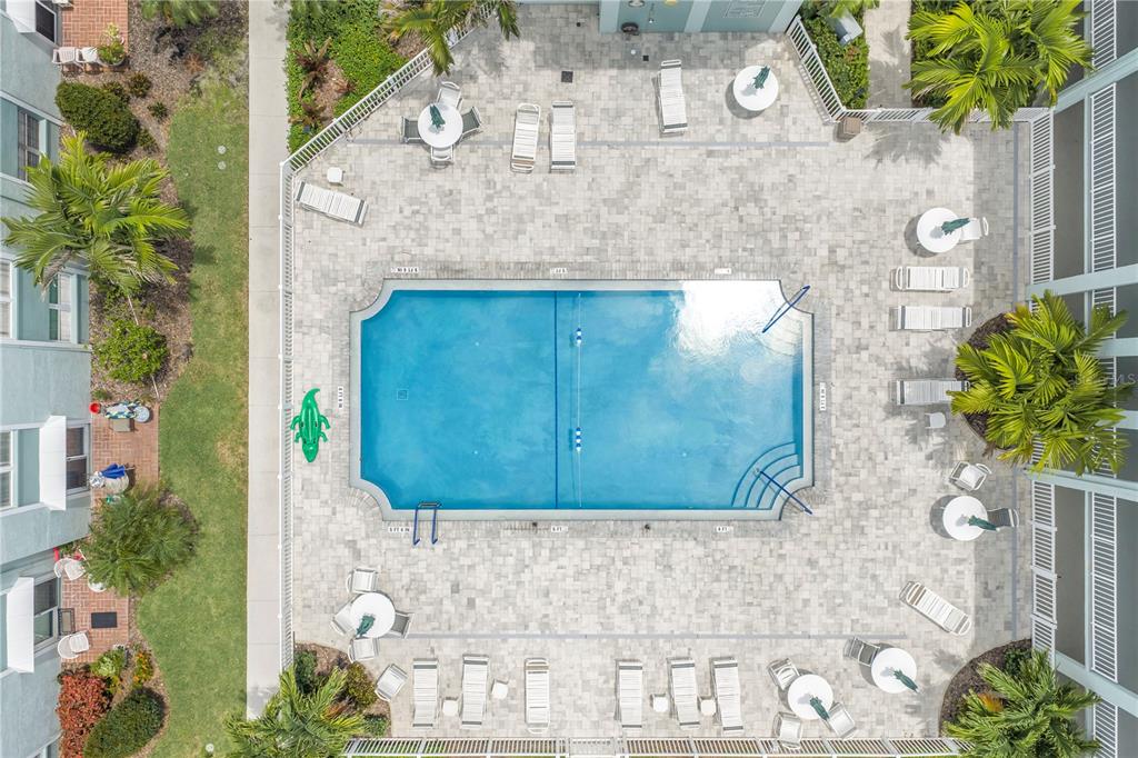An aerial view shows a rectangular swimming pool surrounded by a paved deck and lounge chairs — 701 POINSETTIA ROAD UNIT 116, BELLEAIR, FL