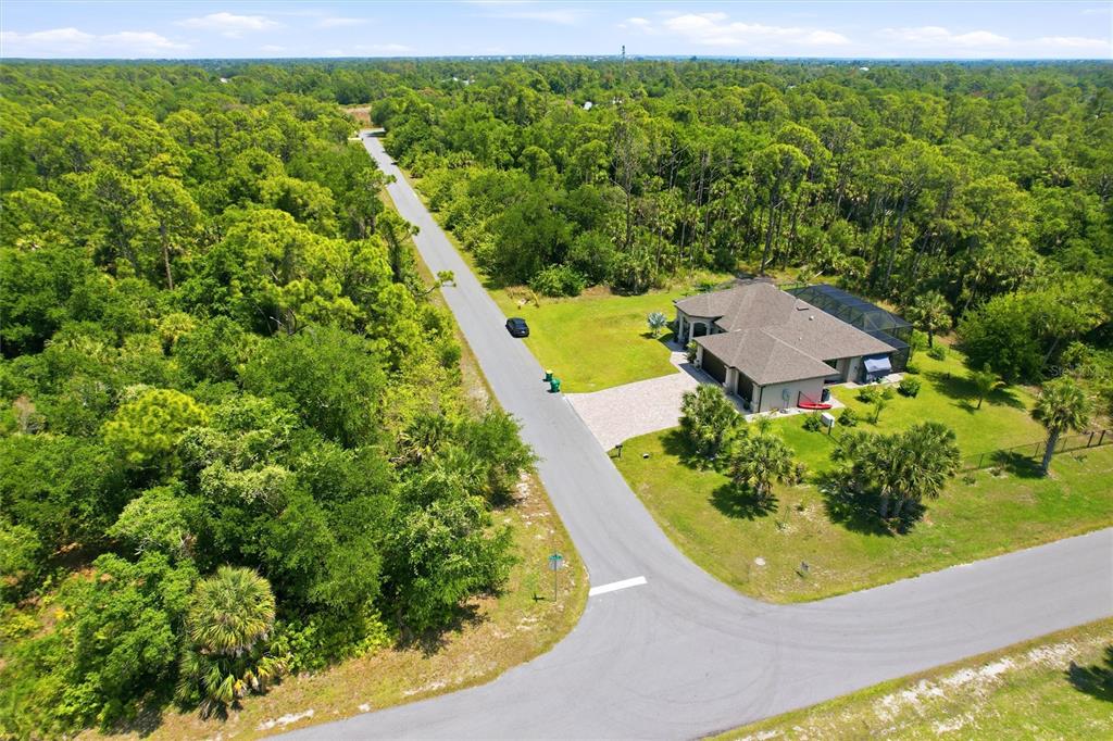 An aerial view shows a house with a pool cage surrounded by dense forest vegetation — 18079 EBER AVENUE, PORT CHARLOTTE, FL