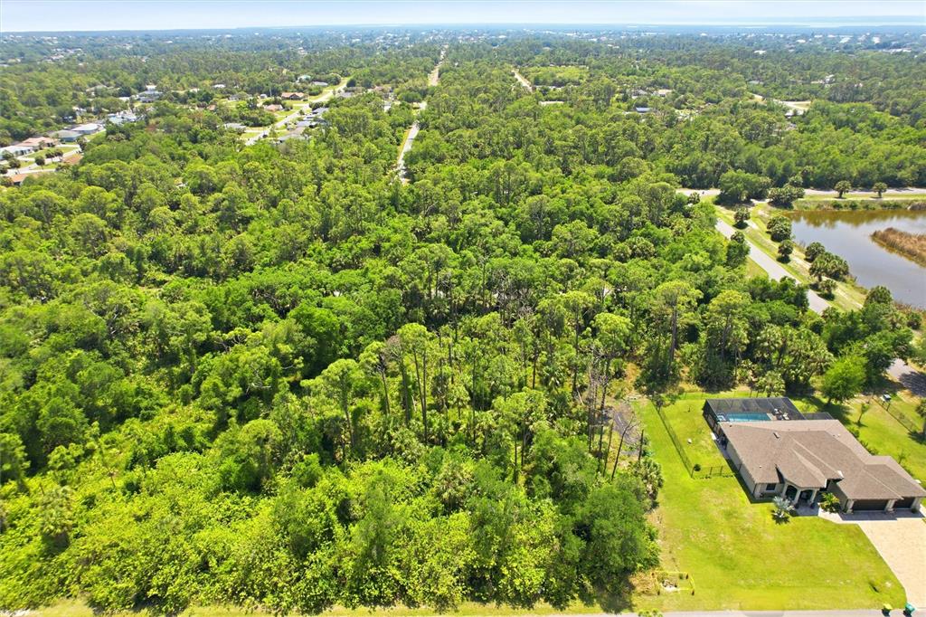 An aerial view shows a house with a pool next to a large wooded area — 18079 EBER AVENUE, PORT CHARLOTTE, FL