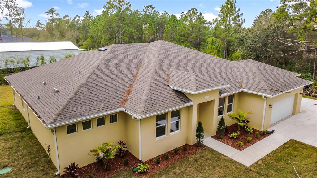 An aerial view of a tan, single-story house with a shingled roof and attached garage — 19022 MARDI GRAS STREET, ORLANDO, FL