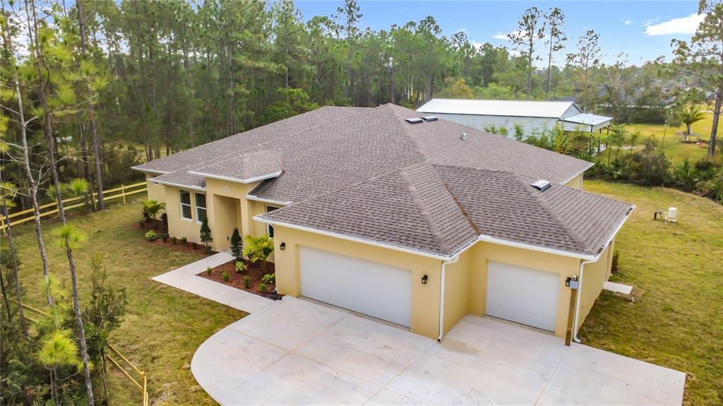 An aerial view of a tan single-story house with a three-car garage and shingled roof — 19022 MARDI GRAS STREET, ORLANDO, FL