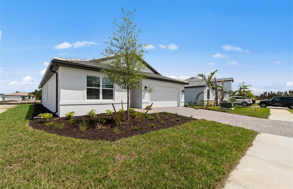 A single-story white house with a paved driveway and a landscaped front yard — 10790 BUTTERCUP COURT, VENICE, FL