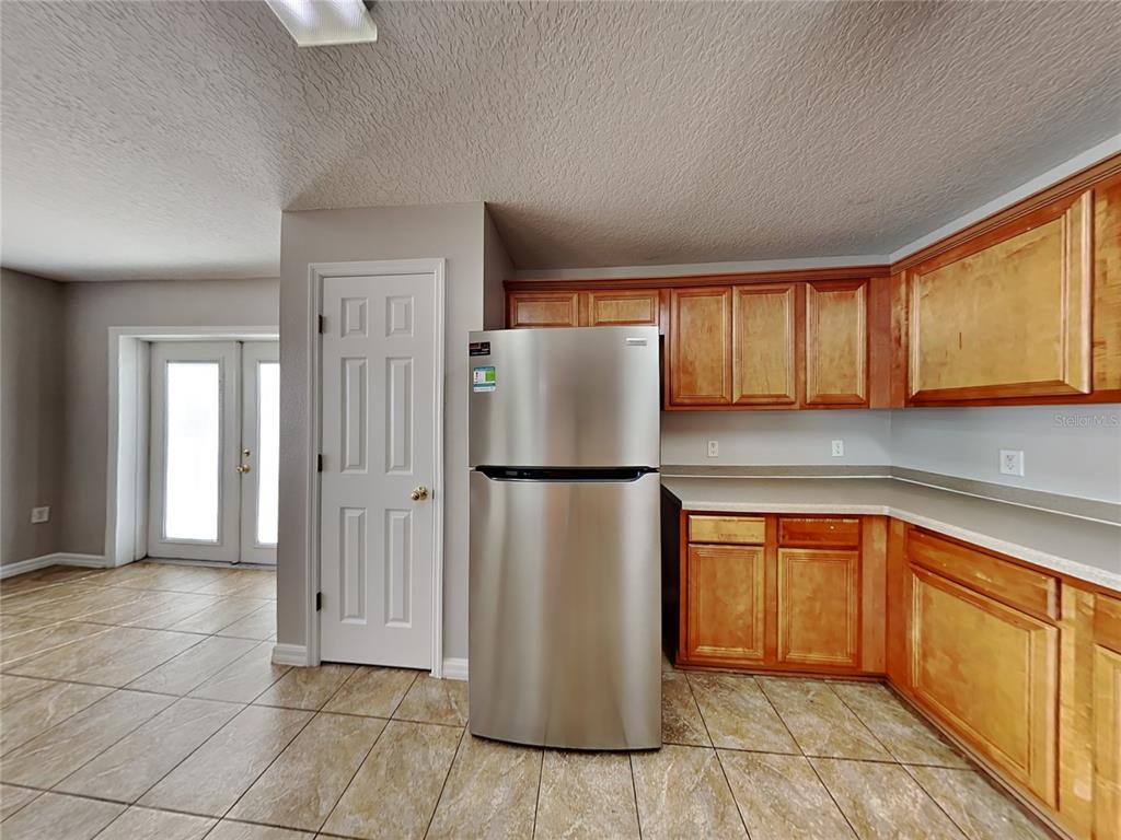 A kitchen features wood cabinets, stainless steel appliances, and tiled flooring — 1388 N PLATTE COURT, KISSIMMEE, FL