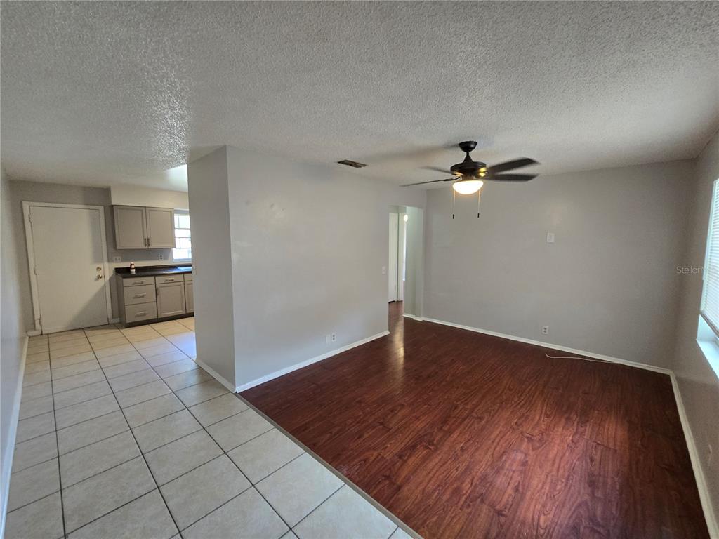 An open-concept living area features wood-look flooring, a ceiling fan, and an adjacent tiled kitchen — 5667 STRUTHERS COURT, WINTER HAVEN, FL