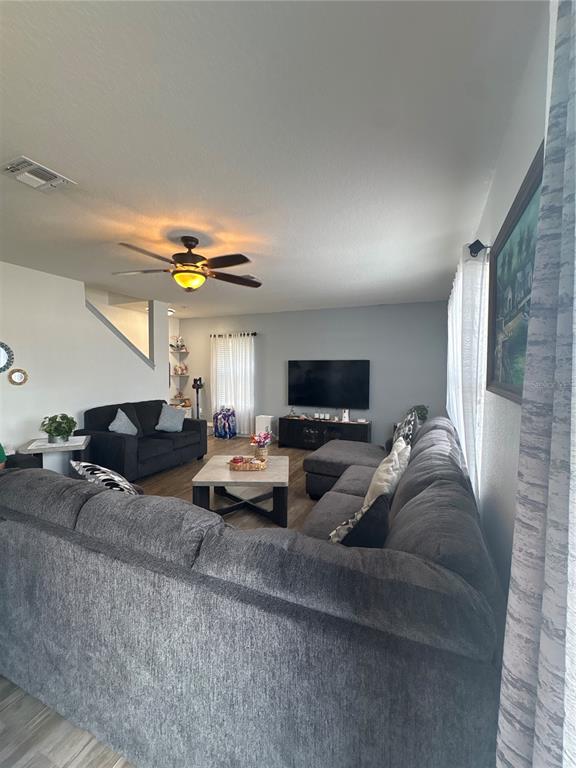 A living room features a large gray sectional sofa, a coffee table, and a television — 5780 LAKESIDE LANDINGS BOULEVARD, WINTER HAVEN, FL