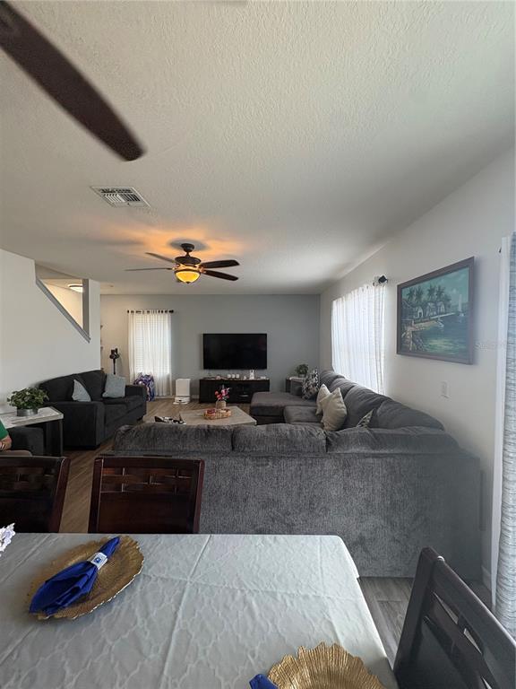 A living room features a large gray sectional sofa, a television, and a dining area — 5780 LAKESIDE LANDINGS BOULEVARD, WINTER HAVEN, FL