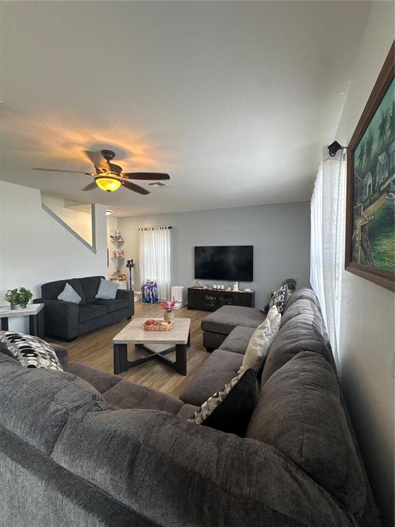 A living room features a large gray sectional sofa, a coffee table, and a television — 5780 LAKESIDE LANDINGS BOULEVARD, WINTER HAVEN, FL