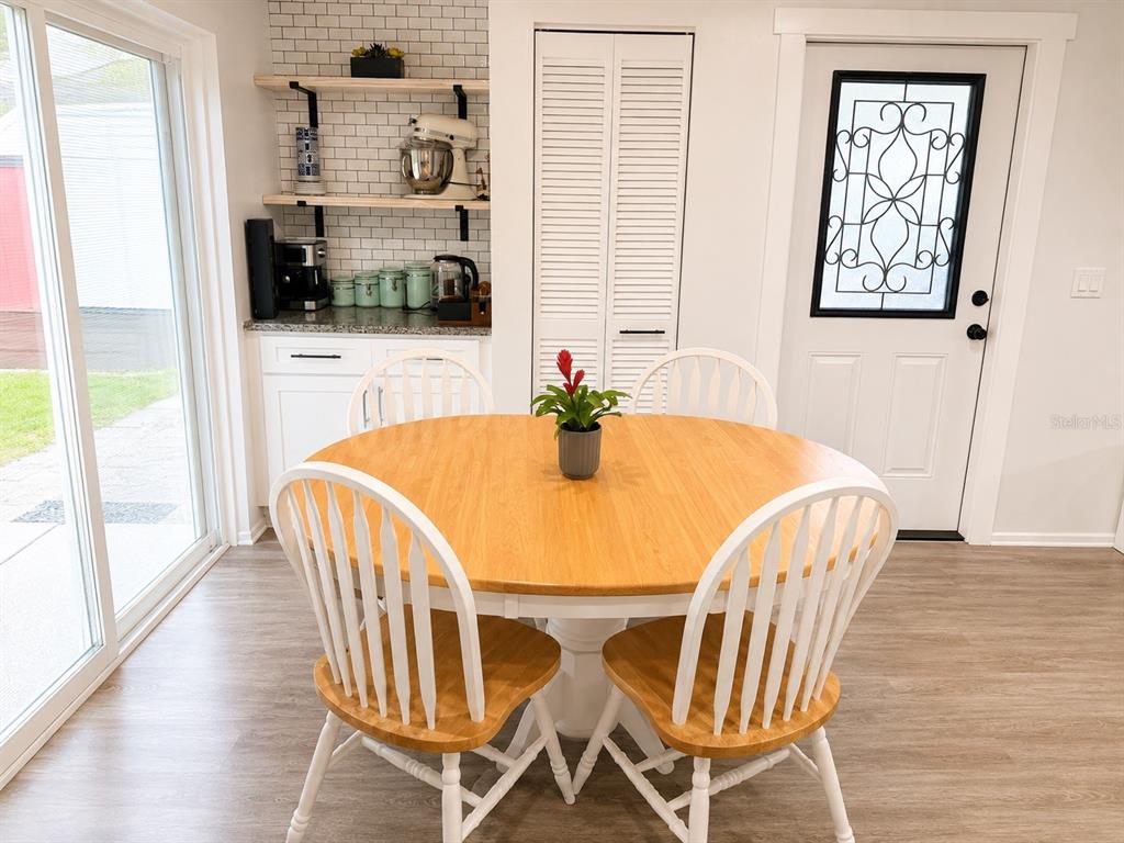 A dining area features a round wooden table, white spindle chairs, and a coffee station — 5117 N TALIAFERRO AVENUE, TAMPA, FL