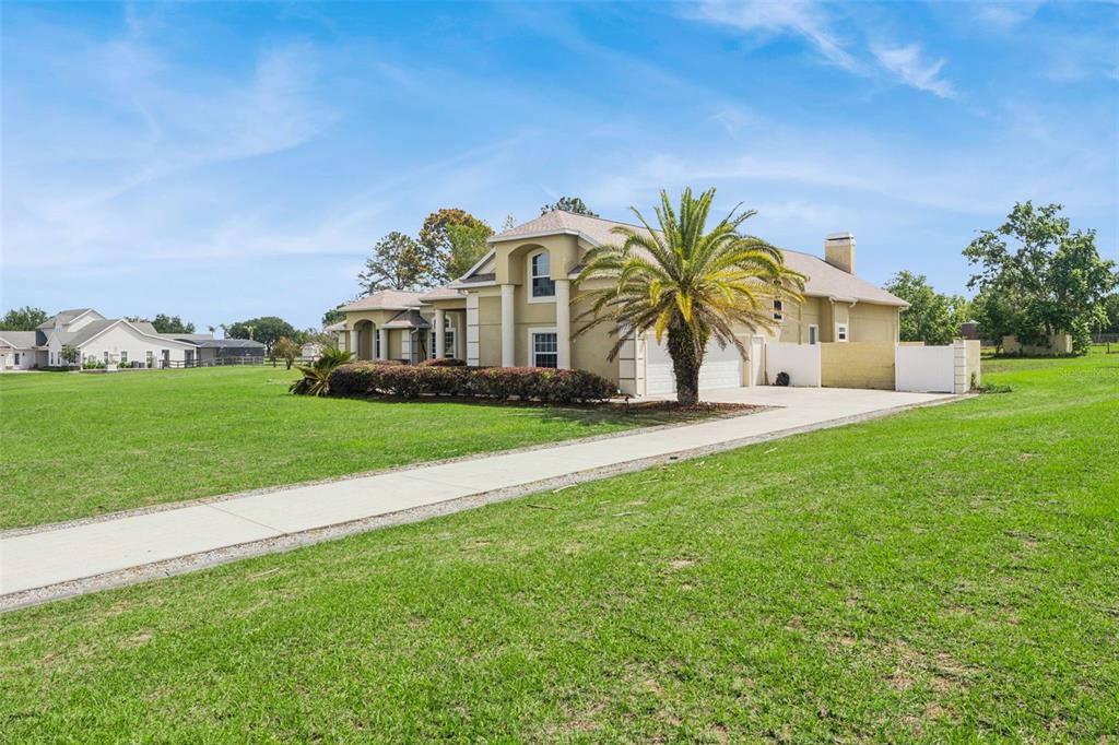 A two-story house with a palm tree, a concrete driveway, and a large grassy yard — 17540 VISTA BELLE COURT, MONTVERDE, FL