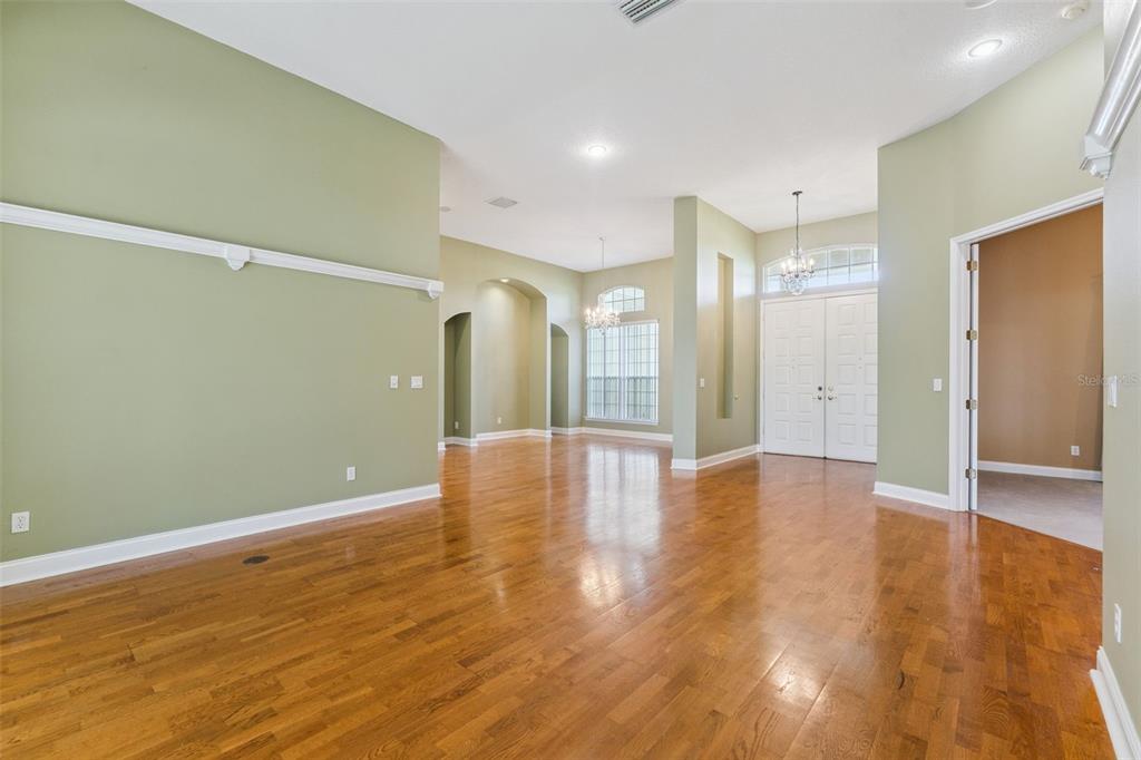 A spacious, empty room with light green walls, hardwood floors, and a high ceiling — 17540 VISTA BELLE COURT, MONTVERDE, FL