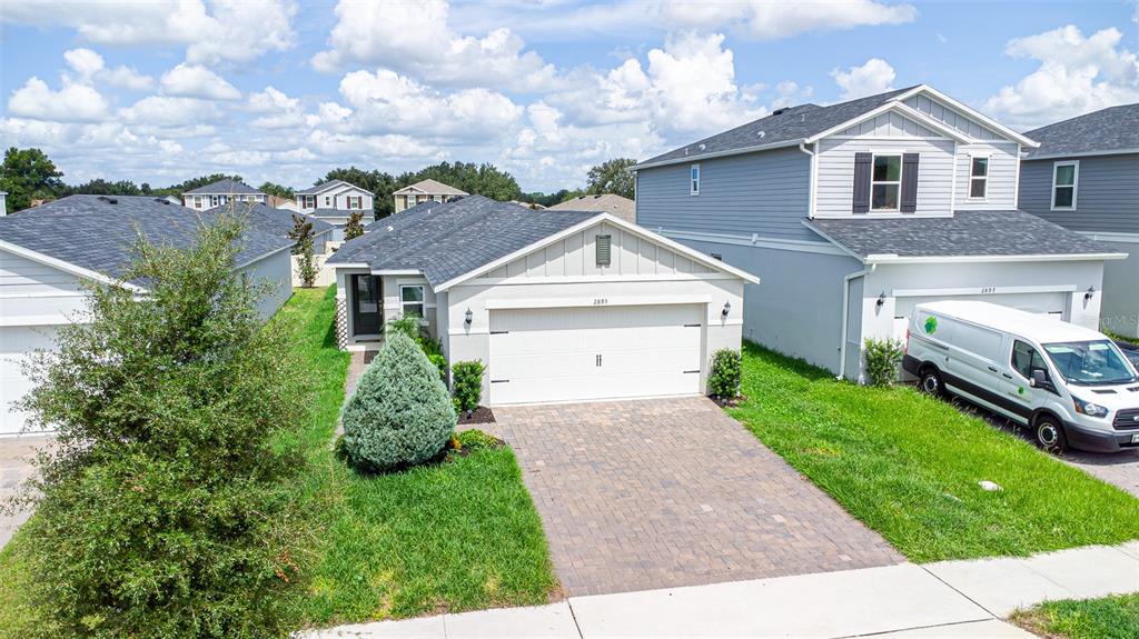 An exterior view of a single-story suburban house with a paved driveway and attached garage — 2893 SANCTUARY DRIVE, CLERMONT, FL