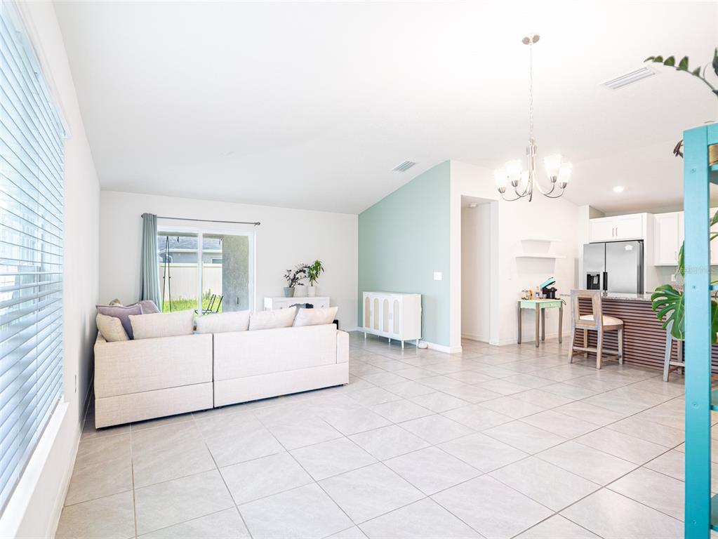 A living room with light tile floors, a beige sofa, and an adjacent open kitchen — 2893 SANCTUARY DRIVE, CLERMONT, FL