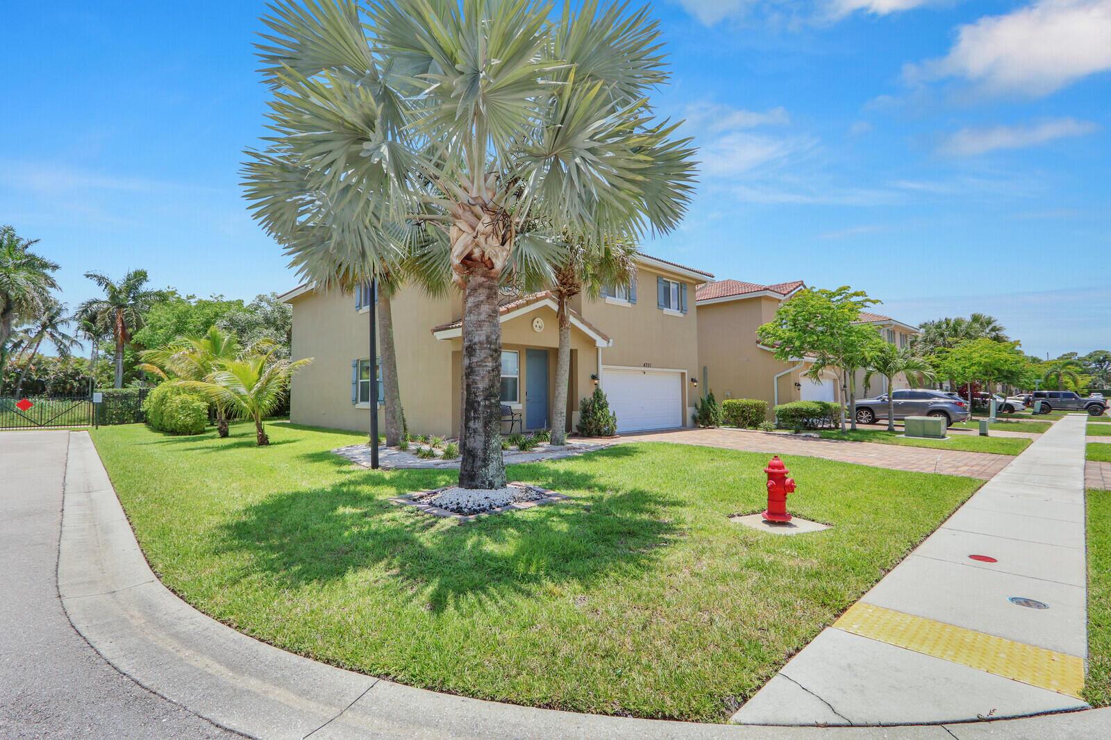A two-story suburban house with a palm tree in the front yard and a fire hydrant — 4701 Foxtail Palm Court, FL 33463, FL