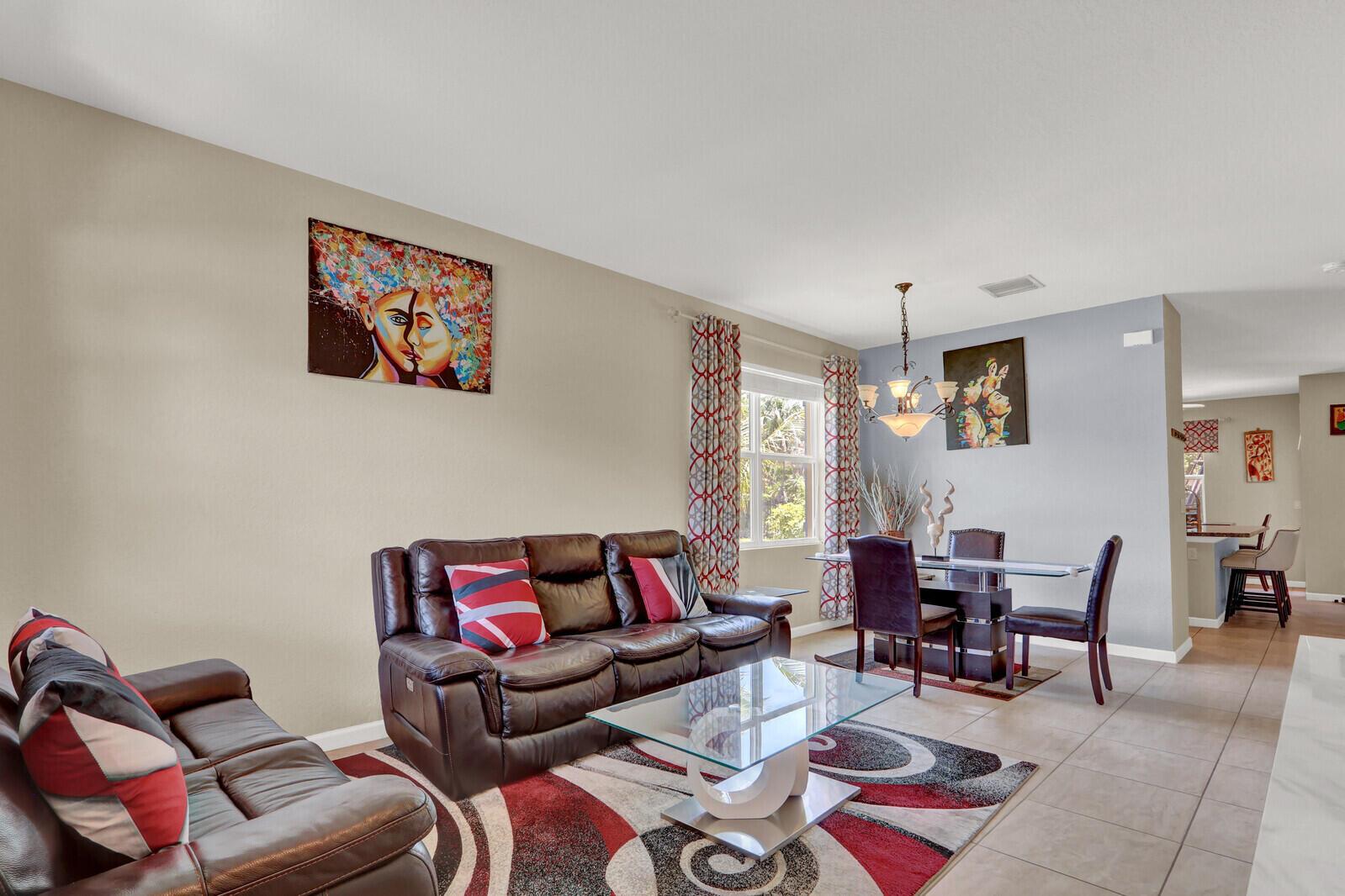 A living and dining area features brown leather sofas, a glass coffee table, and patterned rugs — 4701 Foxtail Palm Court, FL 33463, FL