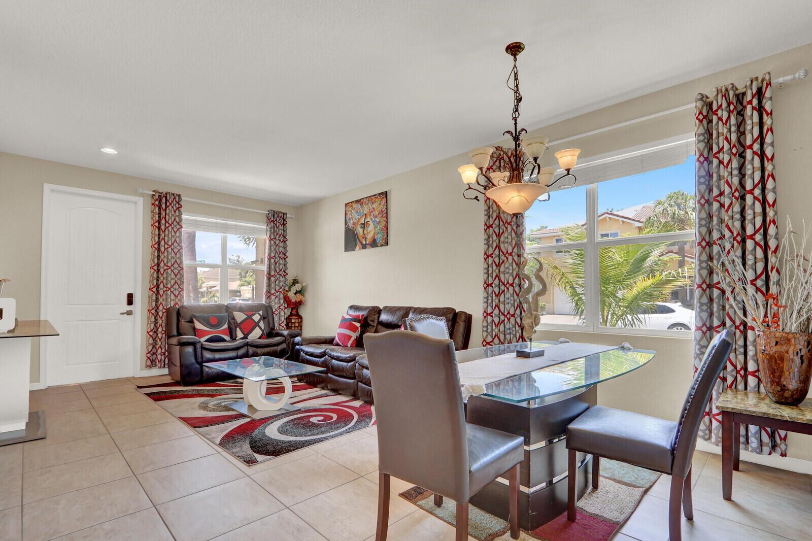 A living and dining area with tile floors, leather furniture, and a glass dining table — 4701 Foxtail Palm Court, FL 33463, FL