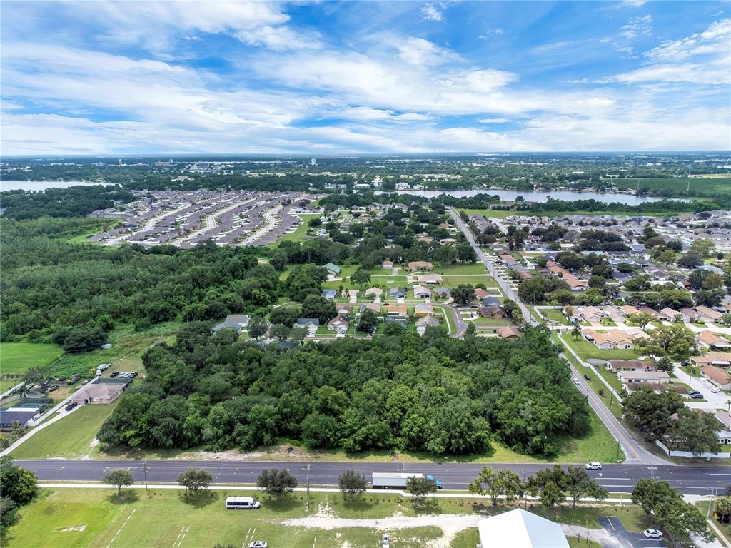 An aerial view shows a large wooded lot bordered by a road and residential neighborhoods — 2400 BUCKEYE ROAD NE, WINTER HAVEN, FL