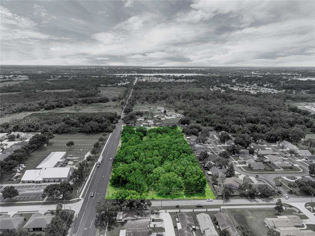 An aerial view shows a rectangular, tree-covered vacant lot bordered by roads and residential neighborhoods — 2400 BUCKEYE ROAD NE, WINTER HAVEN, FL