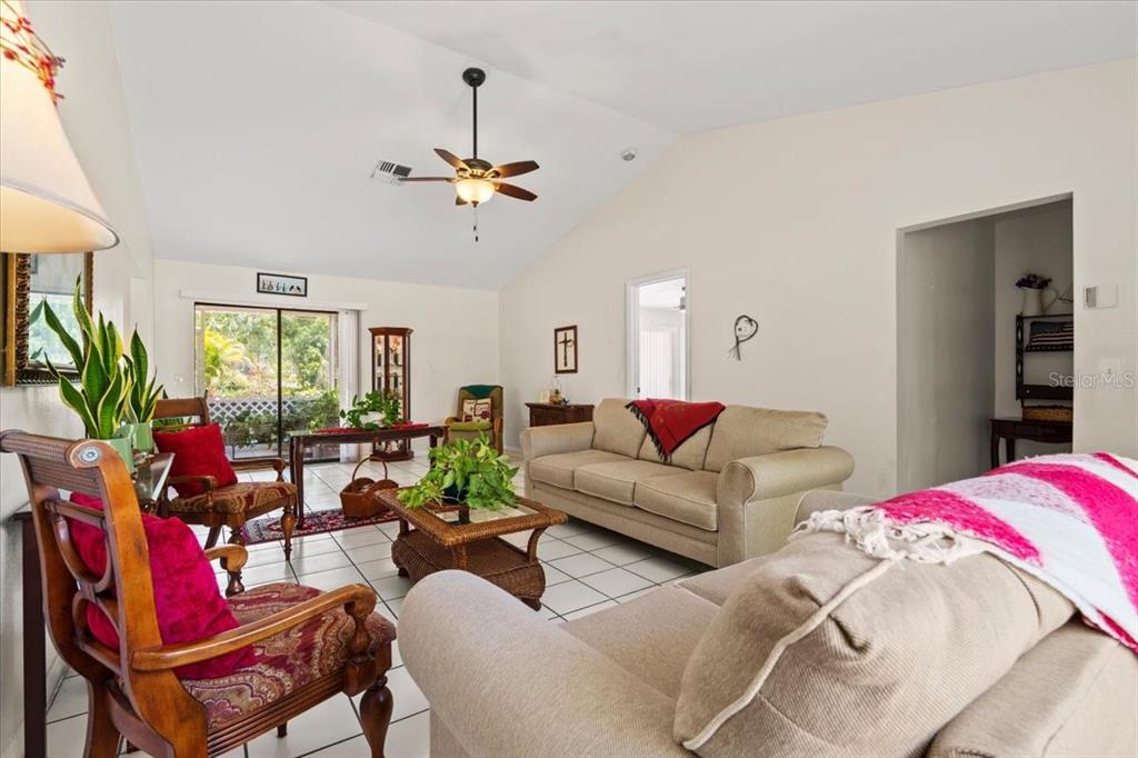 A living room with vaulted ceilings, tile floors, a ceiling fan, and two sofas — 16235 BANYAN AVENUE, PORT CHARLOTTE, FL