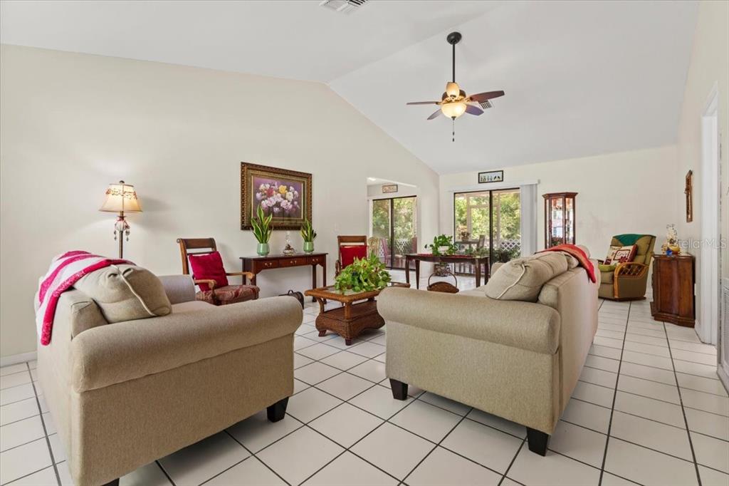 A living room features beige sofas, tile flooring, a vaulted ceiling, and a ceiling fan — 16235 BANYAN AVENUE, PORT CHARLOTTE, FL