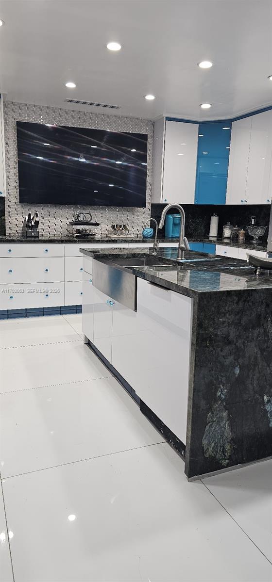A modern kitchen features white cabinets, blue accents, and dark granite countertops with a farmhouse sink — 15700 SW 202nd Ave, Miami FL 33187, MIAMI, FL