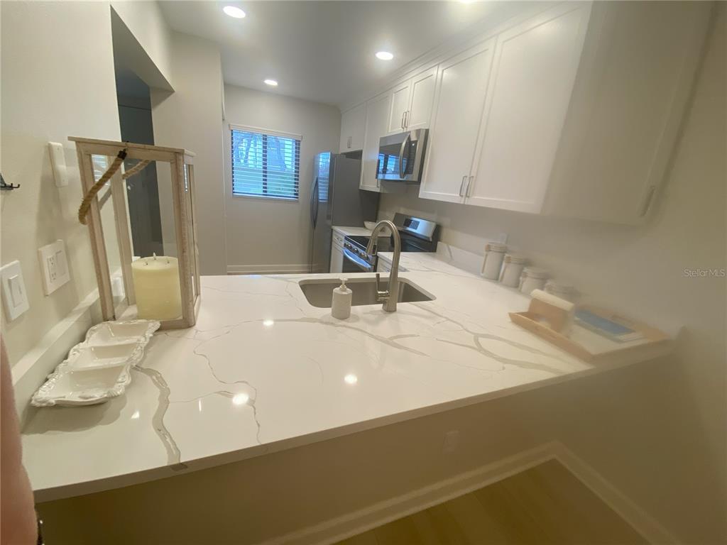 A kitchen features white cabinets, a marble-patterned countertop, and stainless steel appliances — 796 BIRD BAY WAY UNIT Bld 30, VENICE, FL