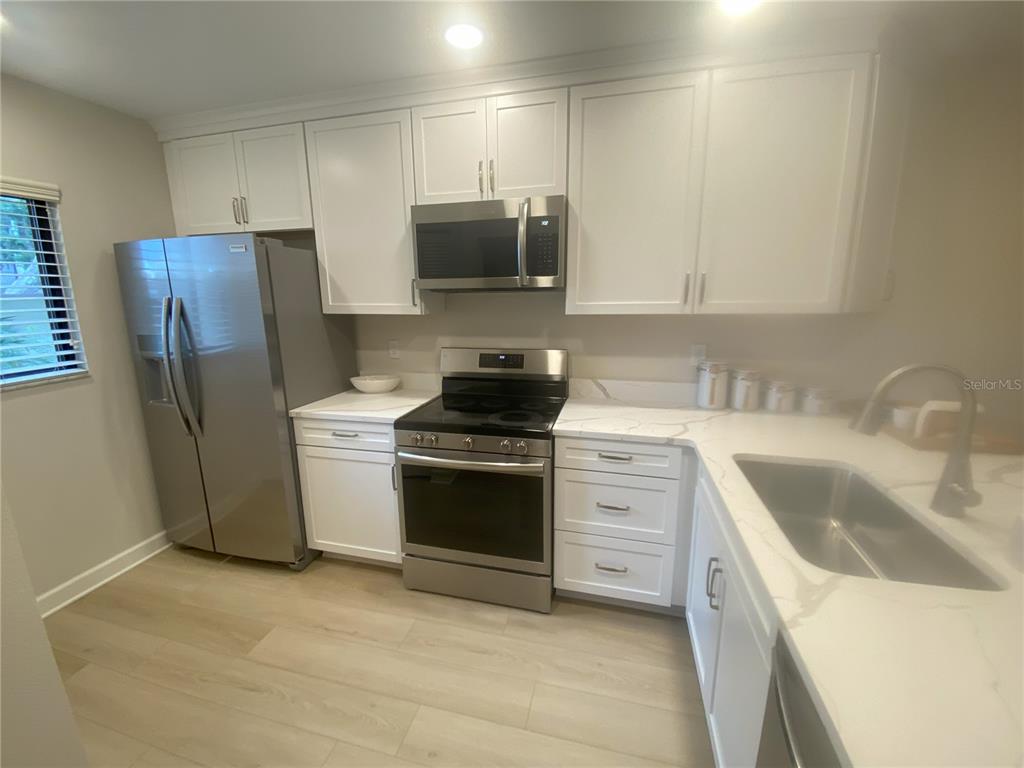 A kitchen with white cabinets, stainless steel appliances, and light-colored countertops — 796 BIRD BAY WAY UNIT Bld 30, VENICE, FL