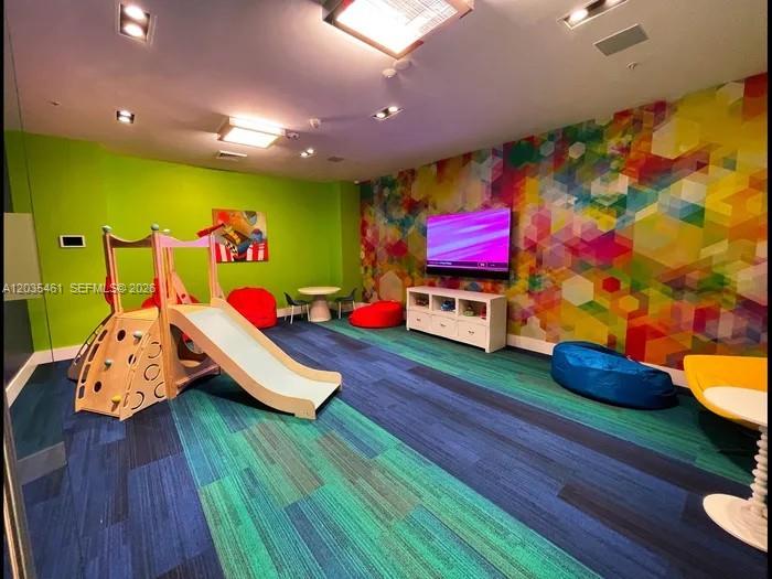 A colorful children's playroom features a wooden slide, beanbag chairs, and a wall-mounted television — 1000 NW 7th St # 310, Miami FL 33136, MIAMI, FL