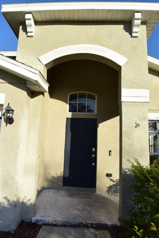 A front entryway features a dark blue door, a decorative arch, and a wall-mounted lantern — 11454 WALDEN LOOP, PARRISH, FL