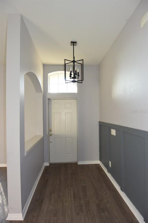 An entryway features a dark wood floor, a modern chandelier, and gray board-and-batten wall paneling — 11454 WALDEN LOOP, PARRISH, FL