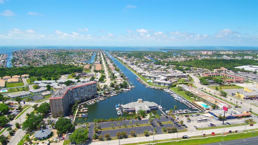 An aerial view shows a multi-story apartment building, a marina, and surrounding residential neighborhoods — 5015 US HIGHWAY 19 UNIT 106, NEW PORT RICHEY, FL