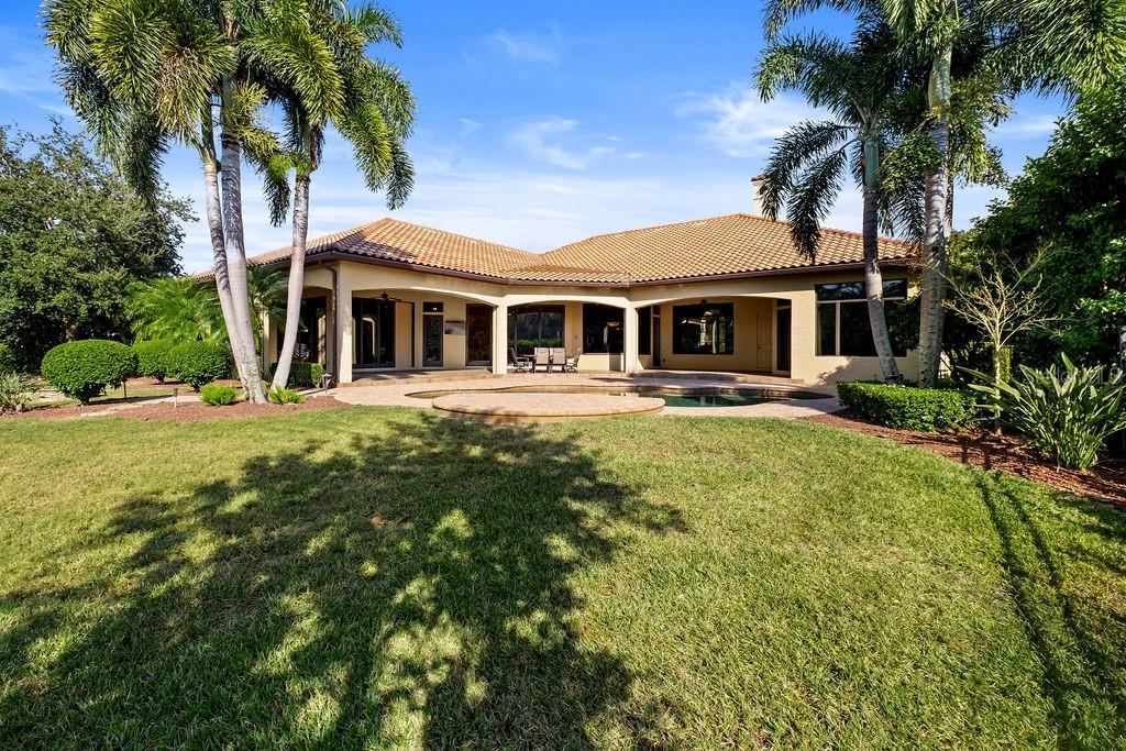 A backyard view of a single-story house with a pool, patio, and palm trees — 6130 GROSVENOR SHORE DRIVE, WINDERMERE, FL