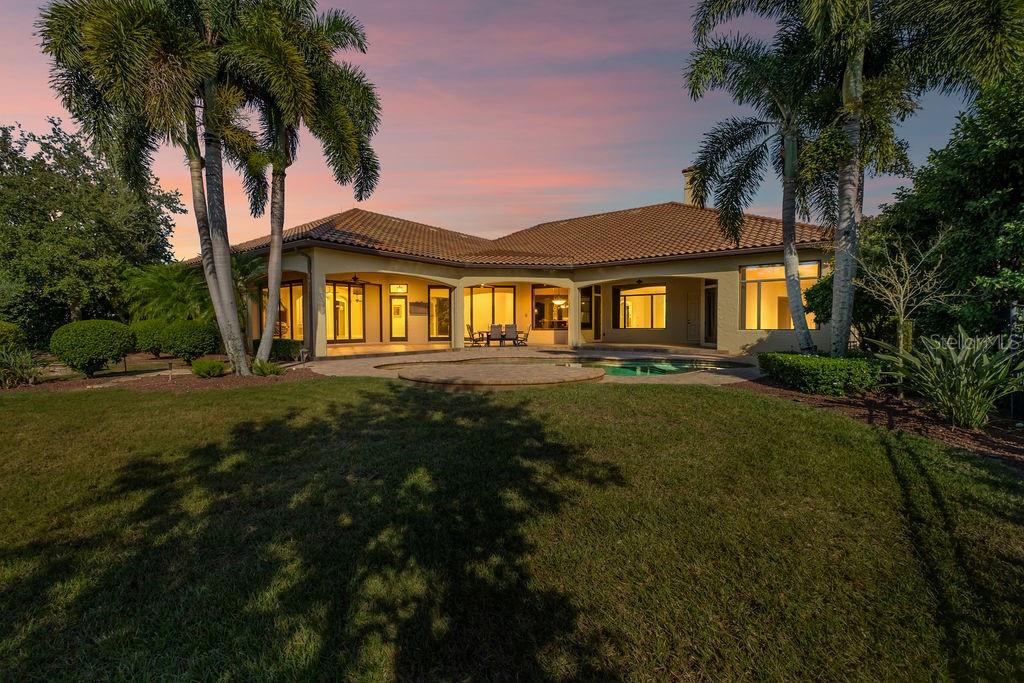 A single-story house with a tile roof, pool, and palm trees at sunset — 6130 GROSVENOR SHORE DRIVE, WINDERMERE, FL