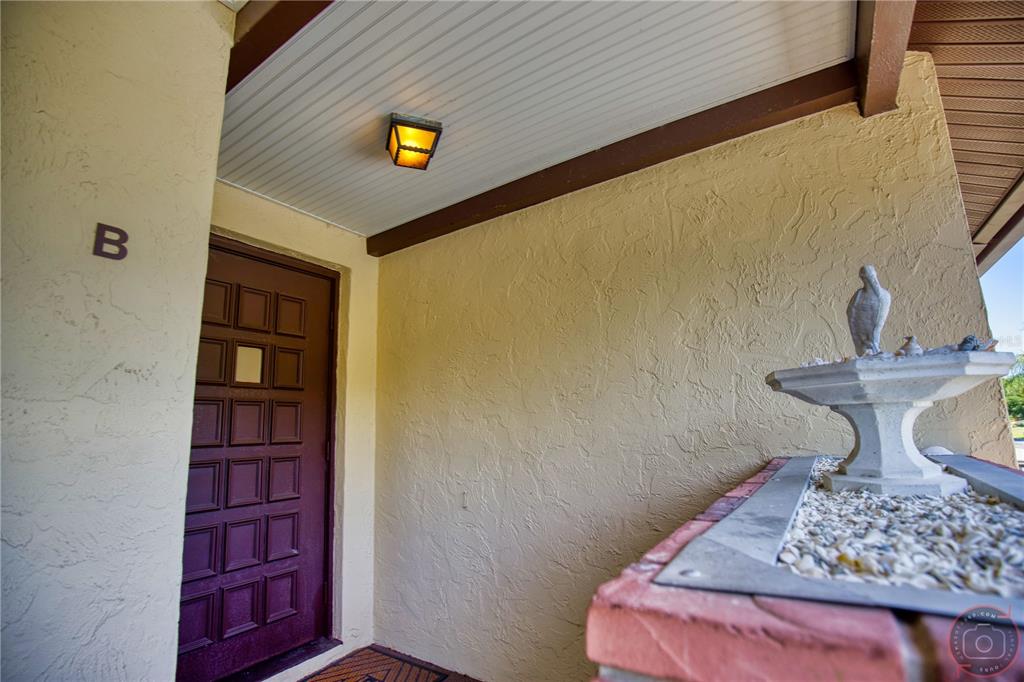 A brown front door with a small window sits under a porch light — 400 MISSION TRAIL E UNIT B, VENICE, FL